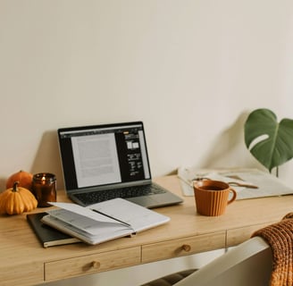 Cozy living: Fall-themed desk with pumpkin decor, lit candle, mug, and warm seasonal accents.