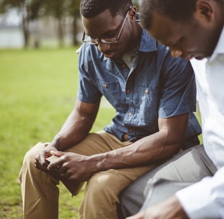 two men sitting on a bench in a park having a spiritual counseling meeting