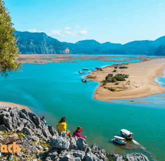 a couple of people standing on a cliff overlooking İztuzu Beach
