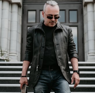 a man in a leather jacket and sunglasses holding a guitar