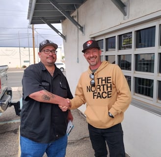 two men shaking hands in front of a building