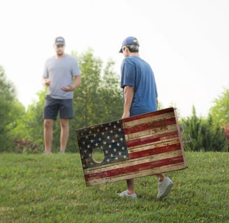 a man holding a corn hole board that is a flag