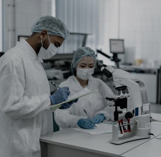 two people in lab coats and masks are looking at a microscope