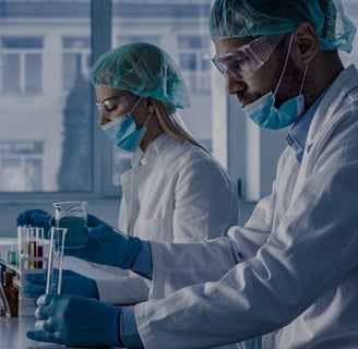 two people in lab coats and masks on a lab