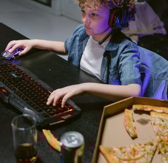 Child playing games on laptop, listening to music and eating fast food