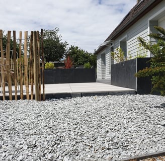 Allée moderne en gravier avec terrasse en dalles et palissade en bois