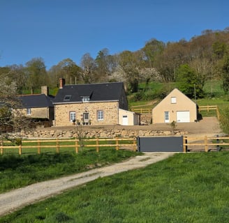 Clôture en bois installée autour d’une maison dans un paysage naturel du Sud-Manche