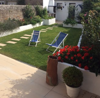 Jardin aménagé avec bordures maçonnées, pelouse soignée et dalles décoratives