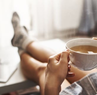 a person sitting on a couch with a cup of coffee