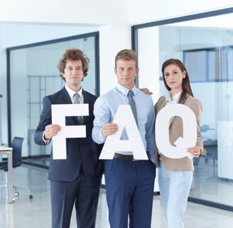 Professionals standing in an office, holding large letters 'FAQ' meaning frequently asked questions