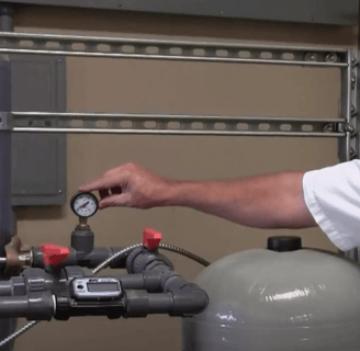 Man pointing to water pressure tank gauge
