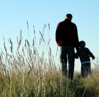 a man and a child are standing in tall grass