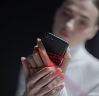 a woman holding a cell phone phone in her hand tied by a red strong. a detox will be necessary.