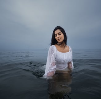 a woman in a white dress is standing in the water