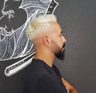 Taglio sfumato con capelli decolorati e barba definita.
