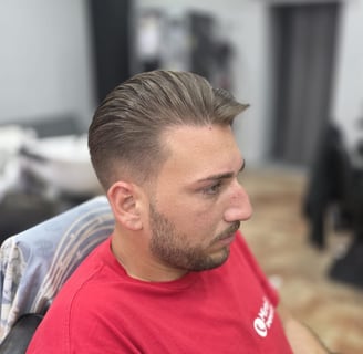 "Taglio classico con sfumatura bassa e ciuffo pettinato all'indietro