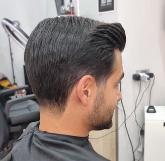 Taglio classico con sfumatura bassa e ciuffo pettinato all’indietro