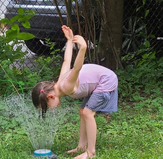 kid in backyard sprinkler