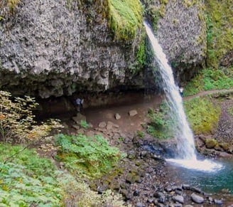 Columbia River Gorge - ponytail falls flows out over a cliff overhang into a blue/green pool