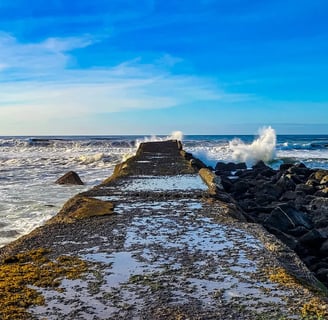 Oregon Coast - A pier jetty next to the lighthouse at a beach in Bandon