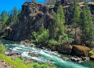 Waterfall Hwy, OR - Dark mountainous boulders, lush green trees, and a dazzling aqua river