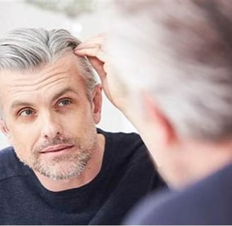 hombre mirándose al espejo las canas