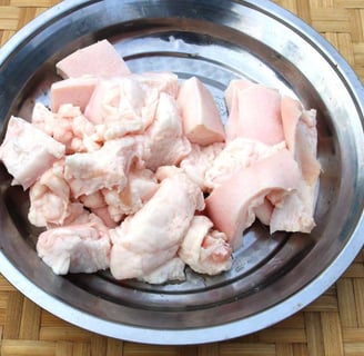 Raw beef fat chunks in a metal bowl, ideal for rendering into beef tallow for cooking or skincare purposes