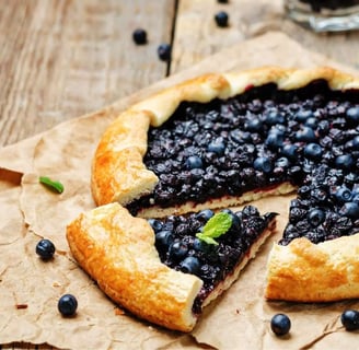 Freshly baked blueberry crostata with a golden crust and vibrant blueberry filling, served on rustic parchment paper