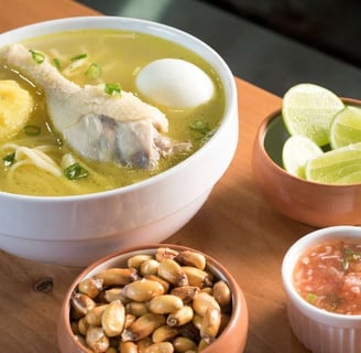 Caldo de pollo with chicken, vegetables, and sides of lime, salsa, and roasted corn nuts