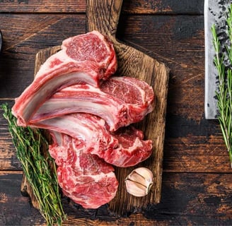 Raw mutton chops with rosemary, garlic, and red peppercorns on a wooden board
