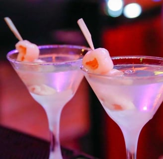 Luxurious Nobu-style lychee martinis, garnished with skewered lychees, glowing in a chic nightlife setting