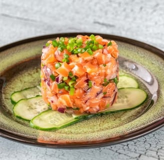 A beautifully plated salmon tartare garnished with fresh herbs and a side of lemon, showcasing a gourmet appetizer