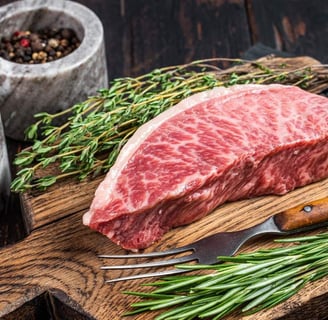 Wagyu Streak on a wooden board along with parsley and a fork, and black pepper