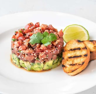 Tuna tartare topped with avocado slices and microgreens, served as a stylish and healthy appetizer option