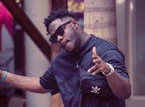 Medikal in dark sunglasses with an Adidas bag.
