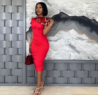 Efia Odo in a red overall dress holding a wine bag.