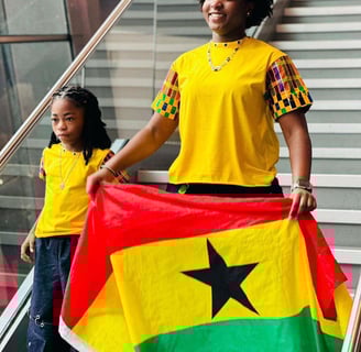 Afronita and Abigail in an African print holding a Ghana Flag.