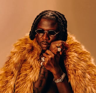 Stonebwoy in dark spectacles with a silky fur around his neck.