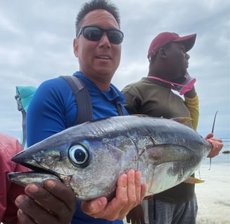 A beginner angler proudly holding a fish caught during a Zanzibar Angler's Paradise fishing trip, wi