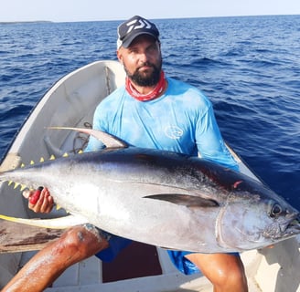 An angler proudly displaying a Tuna caught at one of the best fishing spots in Zanzibar, with a fi