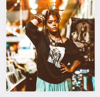 Keri Elle -woman in a skirt and graphic tee is standing in a record store captured by Taye Rose