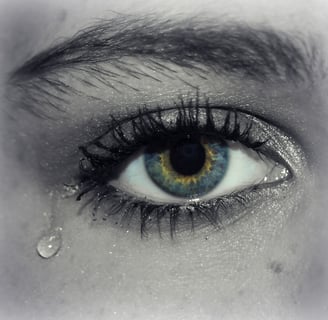 A tear is falling down from the eye of a woman