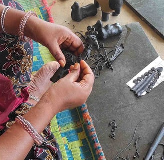 "Tribal artisan shaping wax mold to cast brass idol in traditional lost-wax method"