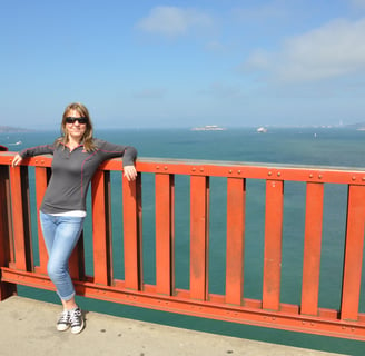 a woman standing on the golden gate bridge over looking at the ocean