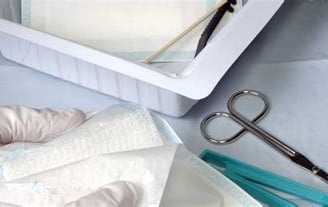 a person in a gloved gloved hand holding a pair of scissors and a