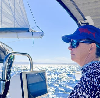 a woman in a blue shirt and sunglasses on a boat