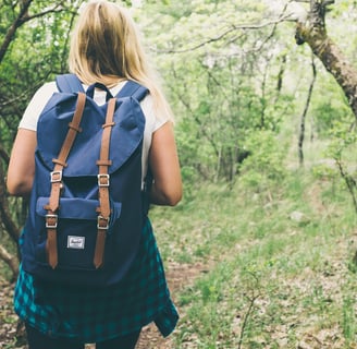 a woman in a blue dress and backpack on a trail