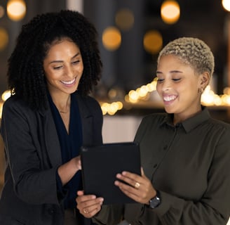 two happy customers standing in front of a table with a tablet