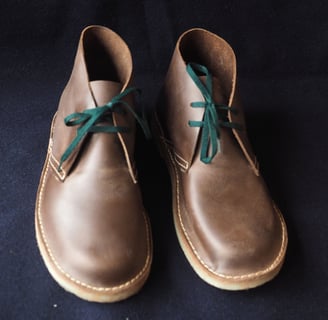 a pair of brown shoes with green laces