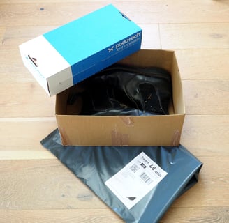 a box of shoes is sitting on a box with returns envelope and foot impression box